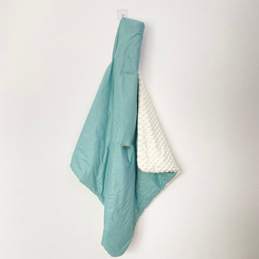 Teal Spot infant snuggle blanket, hanging to show the patterned cotton and cream minky sides